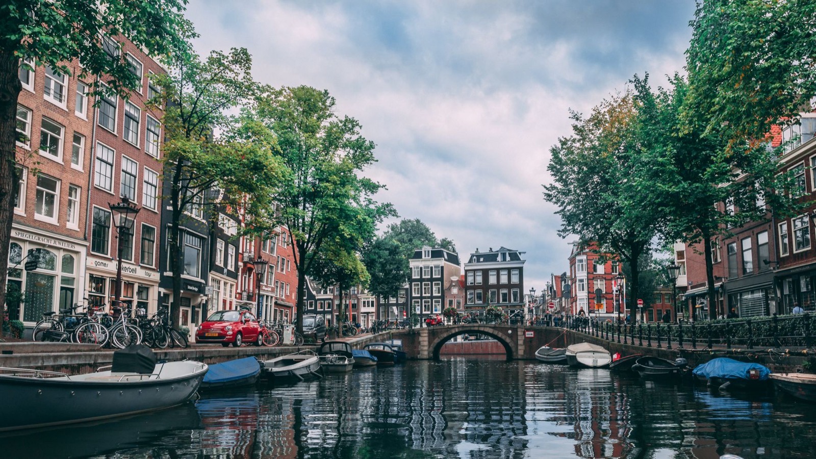 Amsterdamse gracht met brug, boten en bakstenen panden