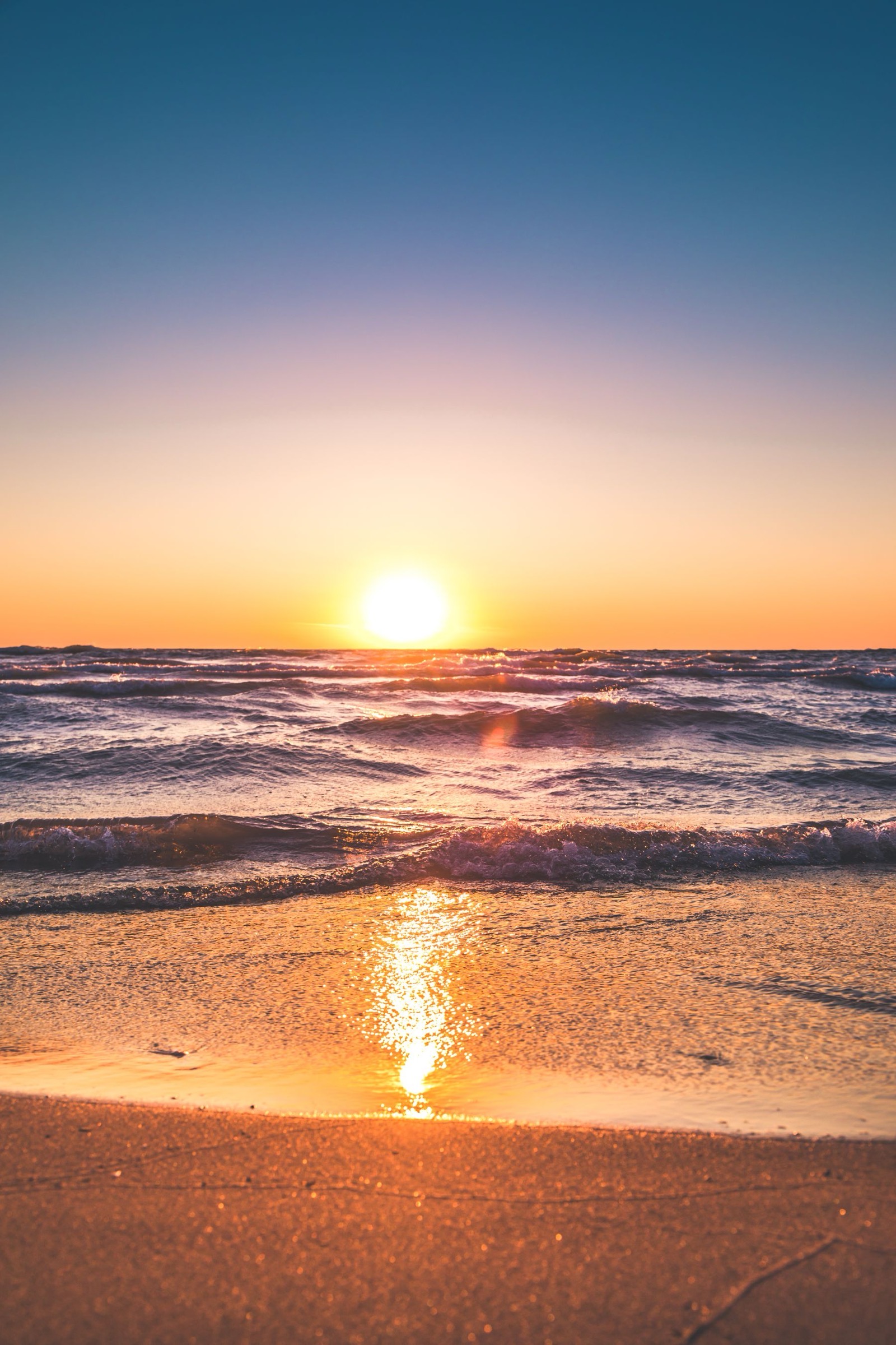 Lage zon boven de branding op een zandstrand